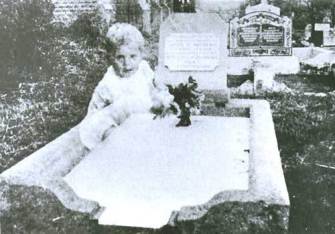 Fantoma unui copilaş apăru pe mormântul "vecinei" sale din cimitir! Cel puţin, asta se vede din poză...